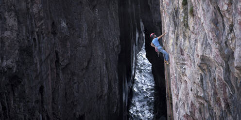 Mann klettert an Felswand auf Berg - ALRF02089