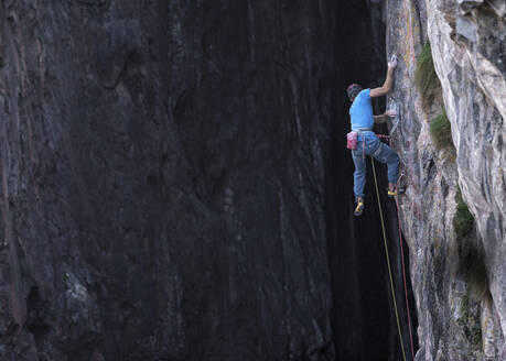 Mann mit Klettergurt klettert auf felsigen Berg - ALRF02091