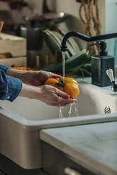 Hände einer Frau waschen frische Tomaten unter dem Wasserhahn in der Küche - VSNF00485