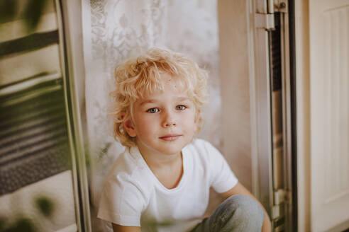Niedlicher Junge sitzt an der Tür eines Wohnmobils - MDOF00636