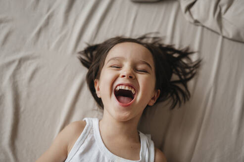 Cheerful boy lying on bed at home - ANAF01005