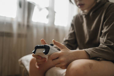 Junge sitzt auf dem Bett mit Controller zu Hause - ANAF01006