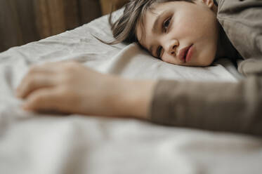 Sad boy lying on bed at home - ANAF01007