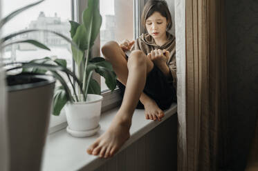 Little girl in underwear sitting on bed looking at smartphone stock photo