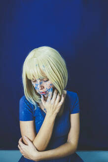 Blond woman covered with blue paint in front of wall - SVCF00344