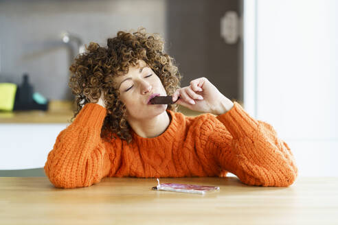 Frau mit geschlossenen Augen genießt Schokolade zu Hause - JSMF02658