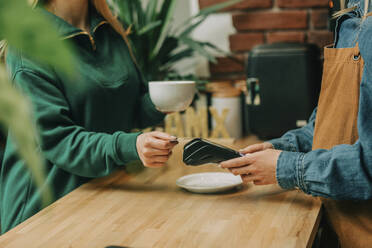 Customer doing contactless payment via credit card at cafe - VSNF00494