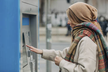 Young woman using ticket vending machine - VSNF00505