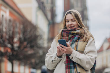 Lächelnde junge Frau mit Mobiltelefon - VSNF00512