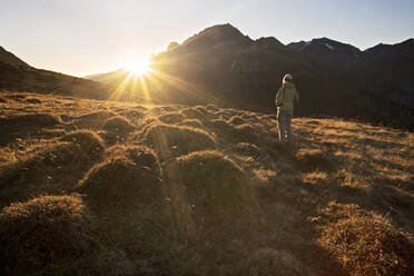 Österreich, Tirol, Wanderin schaut der untergehenden Sonne entgegen - CVF02311