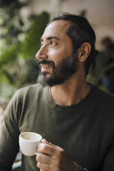 Nachdenklich lächelnder Mann mit Kaffeetasse im Cafe sitzend - JOSEF17170