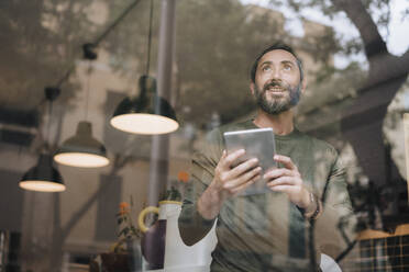 Happy mature man with tablet PC seen through glass - JOSEF17198