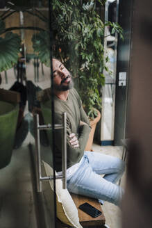 Mann mit geschlossenen Augen sitzt in einem Cafe - JOSEF17226