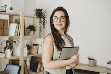 Thoughtful businesswoman wearing eyeglasses standing in office - EBBF08057