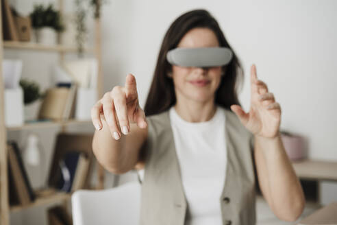 Businesswoman with VR glasses gesturing in office - EBBF08060