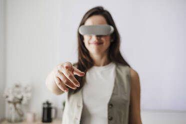 Businesswoman with VR glasses pointing in office - EBBF08064
