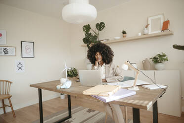 Junge Geschäftsfrau arbeitet am Laptop am Schreibtisch im Büro - RCPF01657