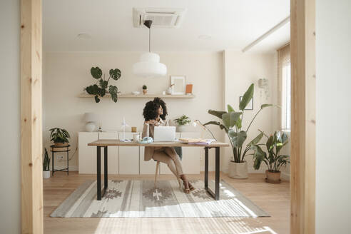 Young businesswoman with Afro hairstyle sitting in office - RCPF01660