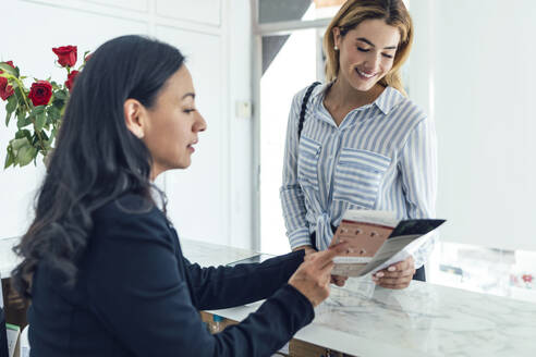 Receptionist showing flyer to customer - JSRF02395