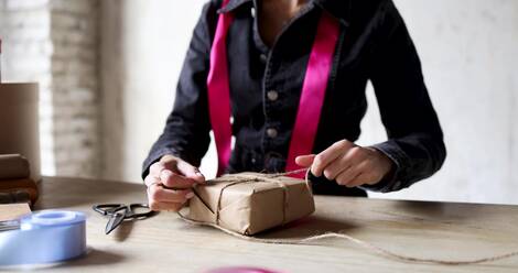 Close-up of a woman cutting gift wrapping paper with sciss…