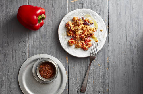 Rohe Paprika, Chilipulver und ein Teller mit verzehrfertigem Couscous - KSWF02299