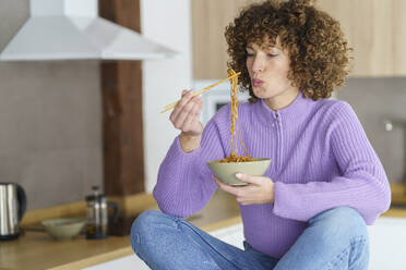 Frau mit Stäbchen isst Nudeln zu Hause - JSMF02686