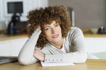 Smiling freelancer leaning on desk at home - JSMF02710