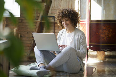 Happy freelancer working on laptop sitting at home - JSMF02715