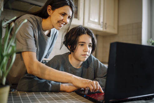 Glückliche Mutter und ihr Sohn benutzen einen Laptop zu Hause - ANAF01021