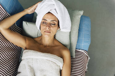 Woman wearing towel relaxing on sofa at home - JJF00230