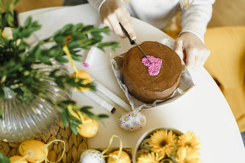 Hands of girl cutting Easter cake on table at home - VBUF00273