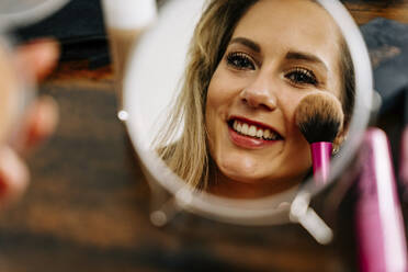 Reflection of woman applying makeup in mirror - JJF00257