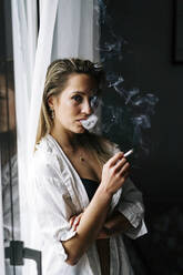 Junge Frau raucht Zigarette zu Hause - JJF00270