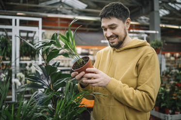 Happy man buying plant in garden center - ANAF01023