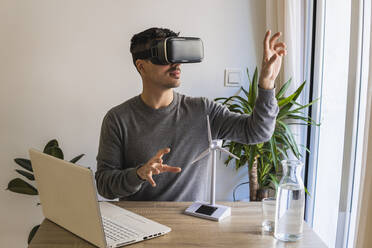 Businessman wearing virtual reality simulator gesturing in office - MGRF00904