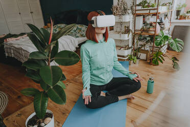 Frau mit Virtual-Reality-Simulator macht Yoga zu Hause - YTF00559