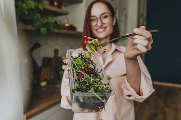 Frau zeigt frischen Salat in der Küche zu Hause - YTF00568