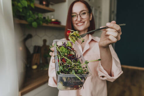 Frau zeigt frischen Salat in der Küche zu Hause - YTF00568