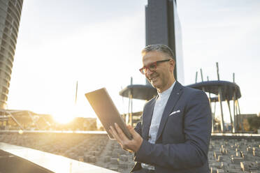 Happy businessman using tablet PC on sunny day - JCCMF09457