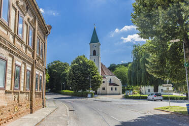 Österreich, Niederösterreich, Kreuzstetten, Leere Straße vor der kleinen Stadtkirche im Sommer - AIF00779