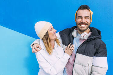 Happy young couple enjoying together in front of blue wall - EGHF00722