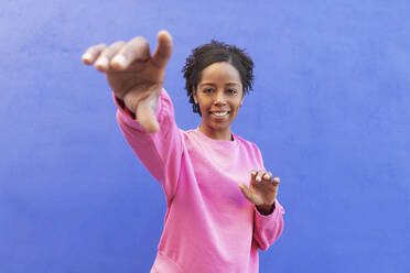 Woman gesturing in front of blue wall - LMCF00198