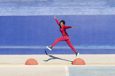 Carefree woman jumping on bollards - LMCF00221