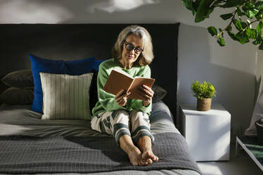 Frau liest Buch auf dem Bett zu Hause - EBSF02837