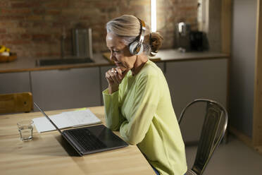 Freiberufler mit drahtlosen Kopfhörern und Laptop am Schreibtisch - EBSF02883