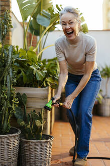 Cheerful mature woman watering plants - EBSF02903