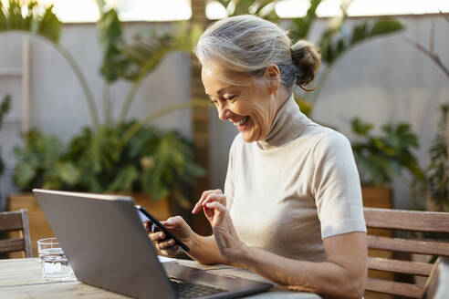 Happy freelancer using mobile phone in back yard - EBSF02912