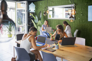 Businesswoman sitting at desk working in office - FBAF02066