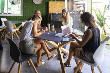 Geschäftsfrauen arbeiten am Laptop und machen Notizen im Büro - FBAF02073