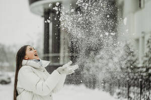 Glückliche Frau beim Schneewerfen im Winter - ANAF01040